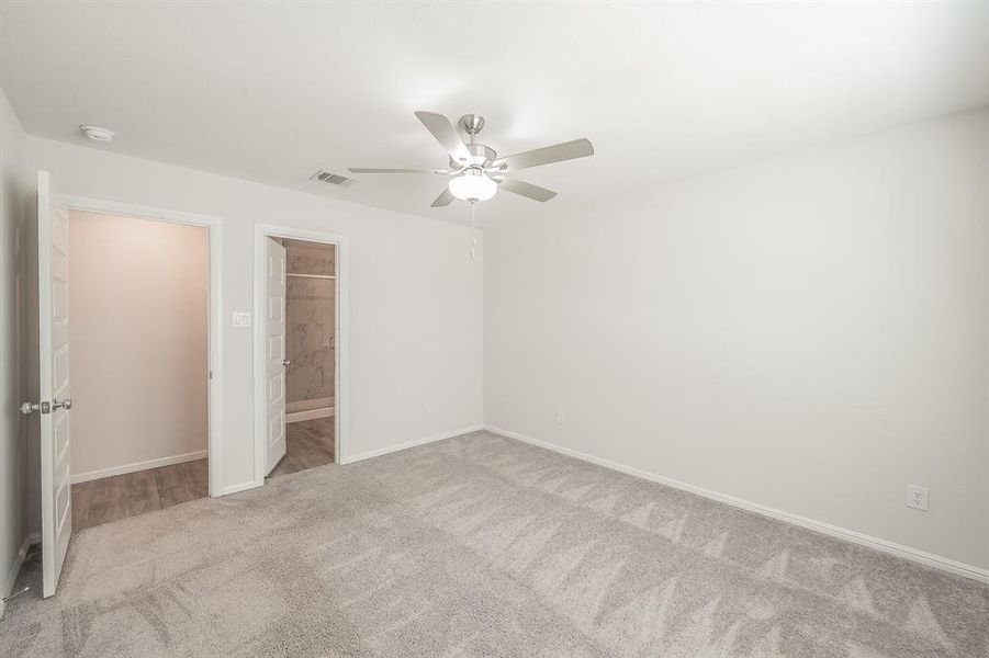 Unfurnished bedroom with light carpet, ceiling fan, and ensuite bathroom Unfurnished bedroom with light carpet, ceiling fan, and ensuite bathroom