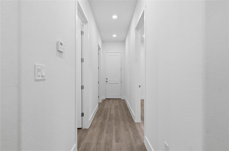 Hallway featuring recessed lighting, wood-finish flooring, white walls, and a white trim package