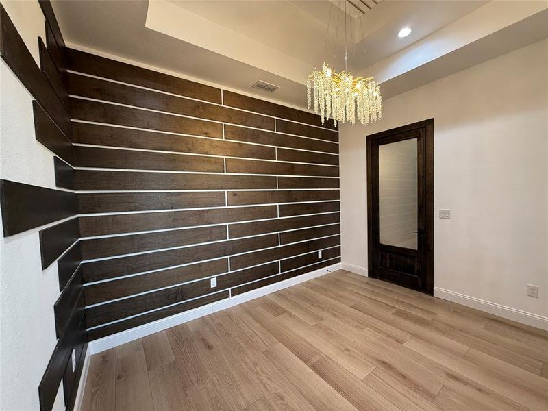Unfurnished dining area featuring a raised ceiling, light wood-type flooring, a chandelier, and recessed lighting Unfurnished dining area featuring a raised ceiling, light wood-type flooring, a chandelier, and recessed lighting