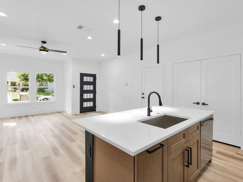 Kitchen featuring light hardwood / wood-style flooring, ceiling fan, an island with sink, decorative light fixtures, and sink