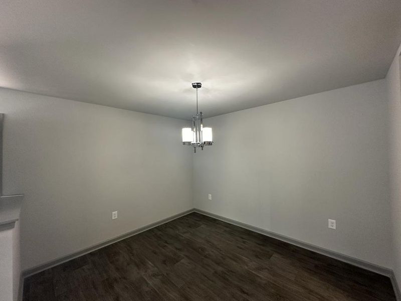 Unfurnished room with dark wood-type flooring and a chandelier