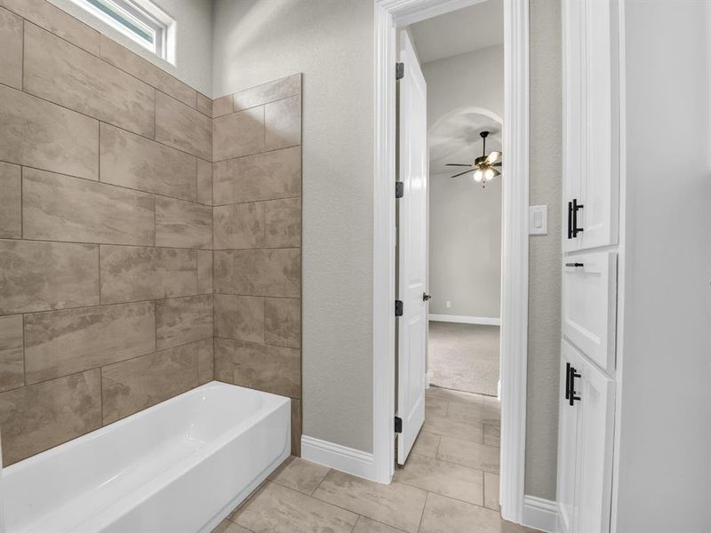 Bathroom featuring tiled shower / bath, ceiling fan, and tile patterned floors