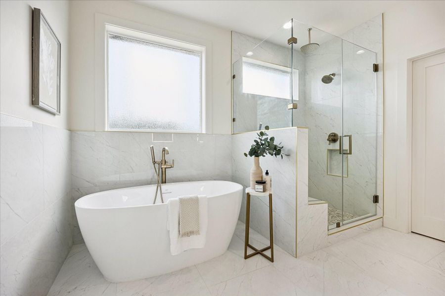 Start and end your day with a little luxury in this spa-inspired ensuite, where a deep freestanding tub, oversized glass-enclosed shower, soft natural light and on-demand hot water make it easy to refresh and recharge.