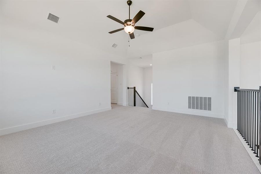 Spare room featuring light carpet, ceiling fan, and vaulted ceiling Spare room featuring light carpet, ceiling fan, and vaulted ceiling