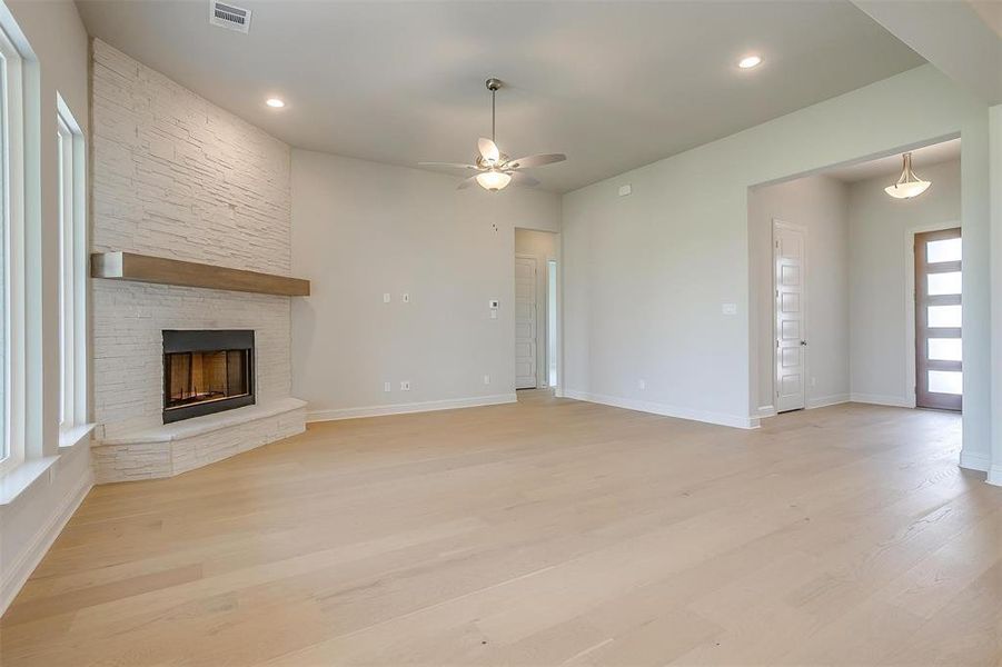 Unfurnished living room featuring light wood-type flooring, ceiling fan, and a fireplace