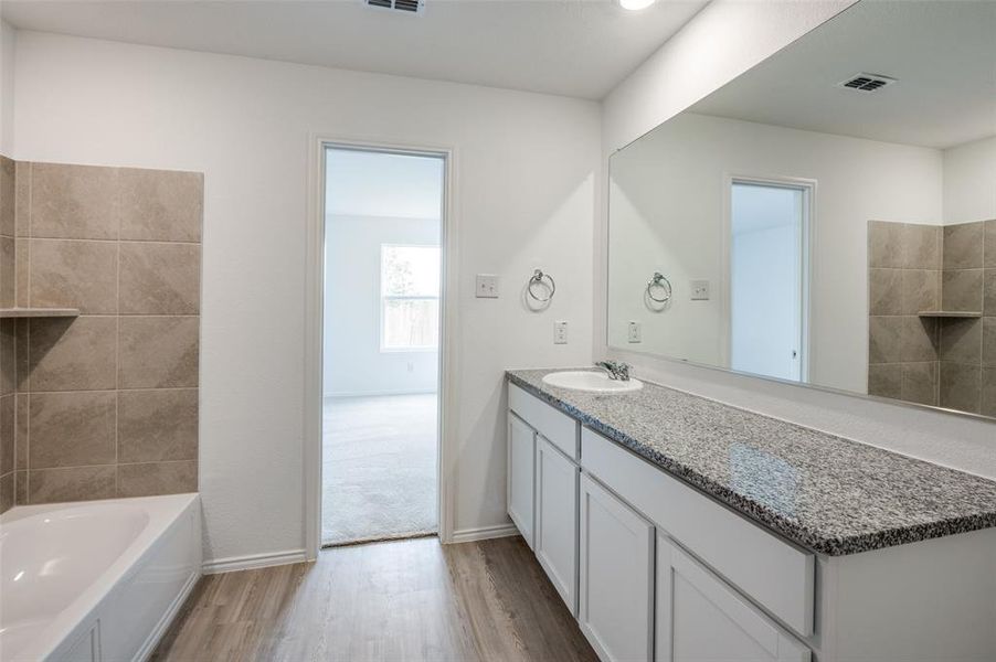 Bathroom featuring hardwood / wood-style floors, vanity, and a tub to relax in