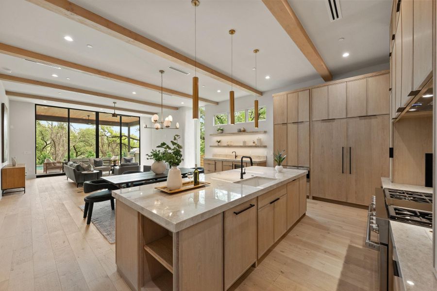 An open-concept living area with soaring ceilings and light wood floors seamlessly connects to a modern kitchen. An open-concept living area with soaring ceilings and light wood floors seamlessly connects to a modern kitchen.