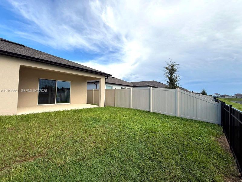 Covered concrete patio, fenced backyard, and sliding glass door entrance