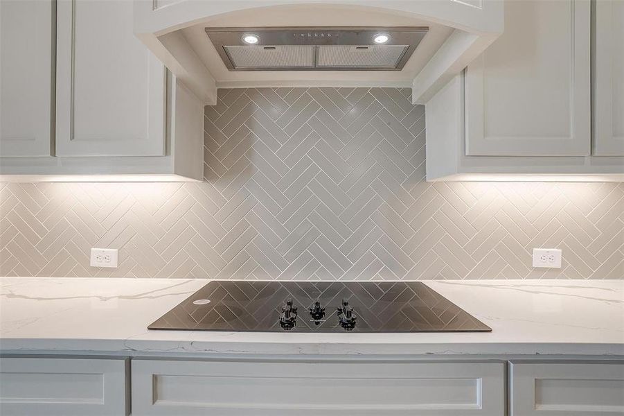 Kitchen featuring white cabinetry, decorative backsplash, and light stone counters