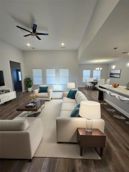 Living room with ceiling fan with notable chandelier and wood-type flooring