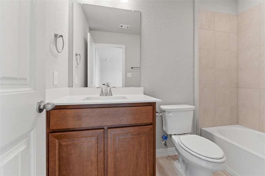 Bathroom with vanity, a textured wall, and shower / tub combination