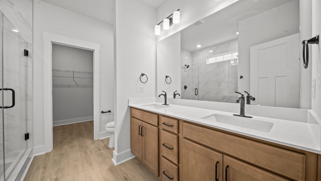 Elegant primary bathroom featuring a spacious walk-in shower and dual vanity in this first-class DRB Homes design