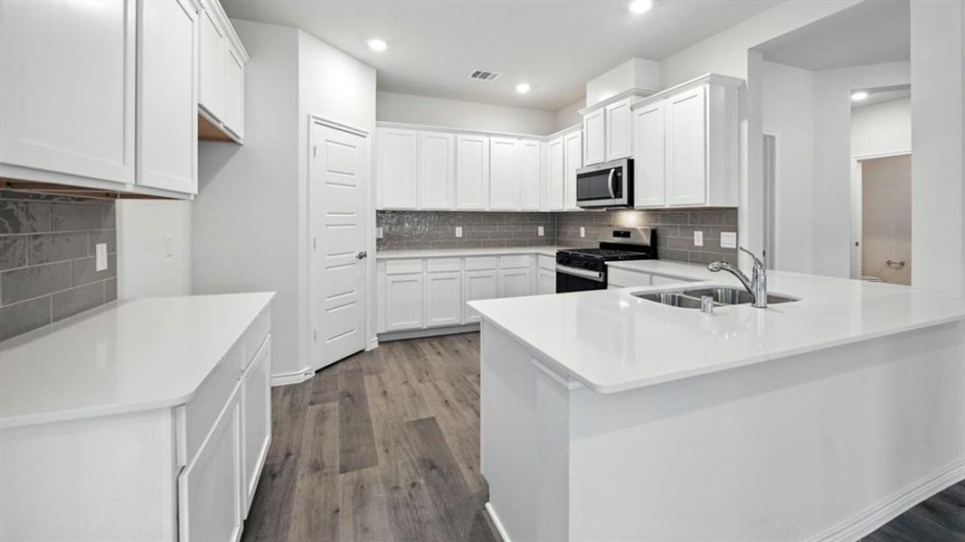 Kitchen featuring white cabinets, stainless steel appliances, backsplash, light stone counters, and a peninsula Kitchen featuring white cabinets, stainless steel appliances, backsplash, light stone counters, and a peninsula