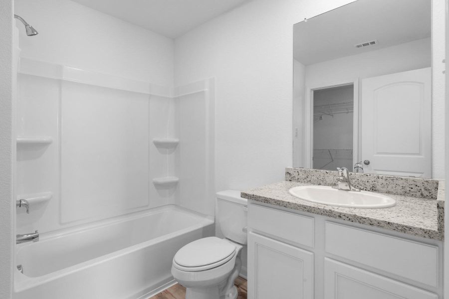 Bathroom featuring vanity, bathtub / shower combination, a walk in closet, and light wood finished floors