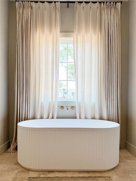 Primary bath features a Freestanding white soaking tub with fluted detailing Primary bath features a Freestanding white soaking tub with fluted detailing
