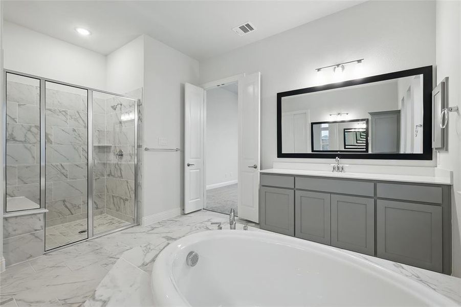 Bathroom with a stall shower, marble finish flooring, a bathtub, vanity, and baseboards