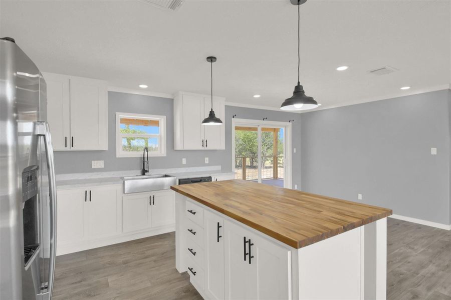An open kitchen centers on a wood-topped island set against modern recessed lighting.