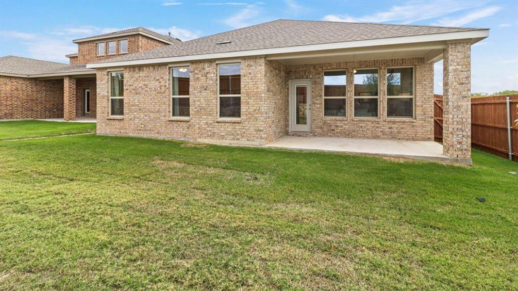Rear view of house with a patio area, a lawn, and brick siding