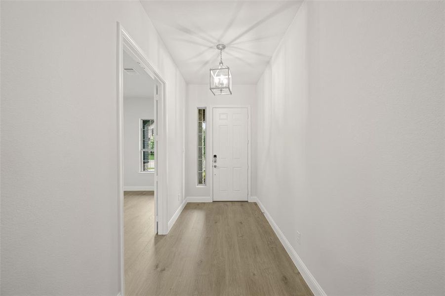 Foyer entrance with light wood-style flooring and a chandelier
