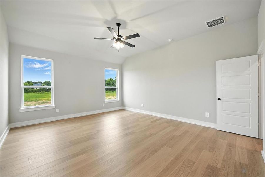 Spare room with light wood finished floors, healthy amount of natural light, and a ceiling fan Spare room with light wood finished floors, healthy amount of natural light, and a ceiling fan