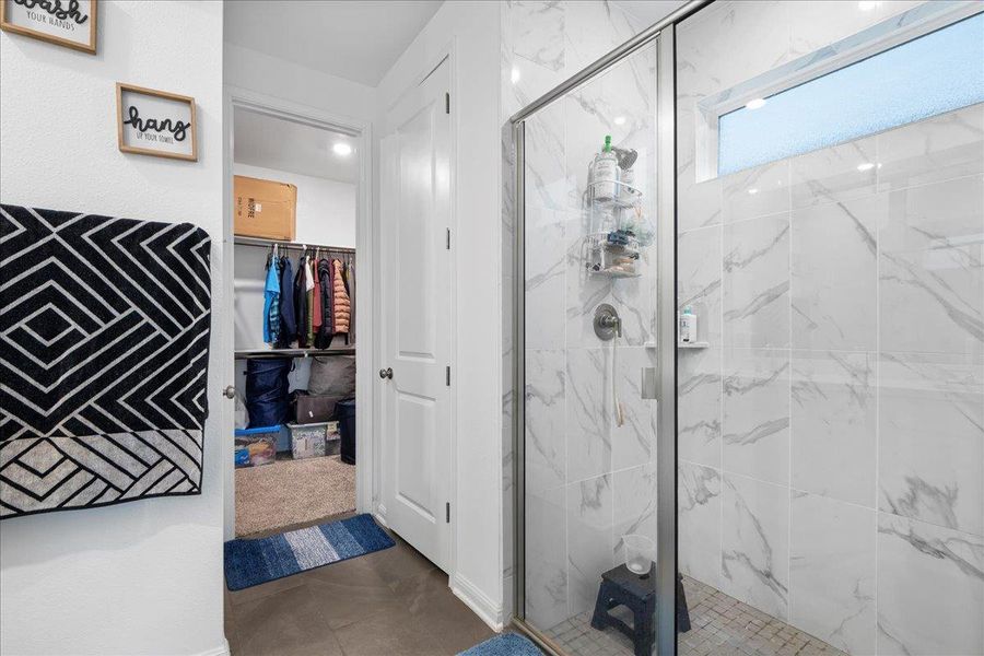 Full bath with a marble finish shower and a spacious closet