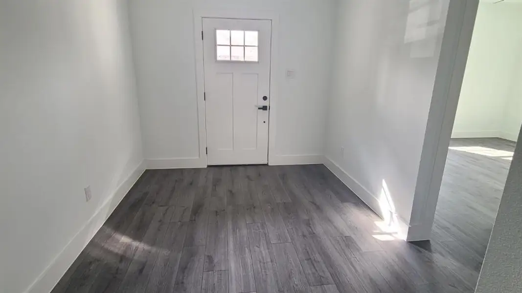 Entryway featuring wood-finish flooring, white baseboards, and a white door with a clear glass pane Entryway featuring wood-finish flooring, white baseboards, and a white door with a clear glass pane