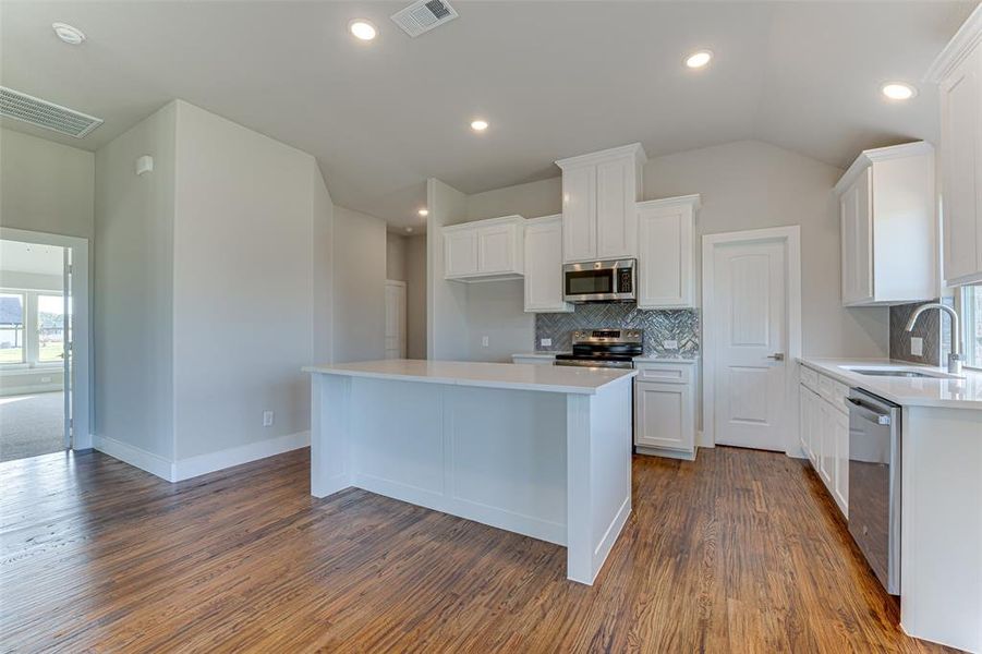 Kitchen featuring stainless steel appliances, sink, white cabinets, a center island, and dark hardwood / wood-style floors