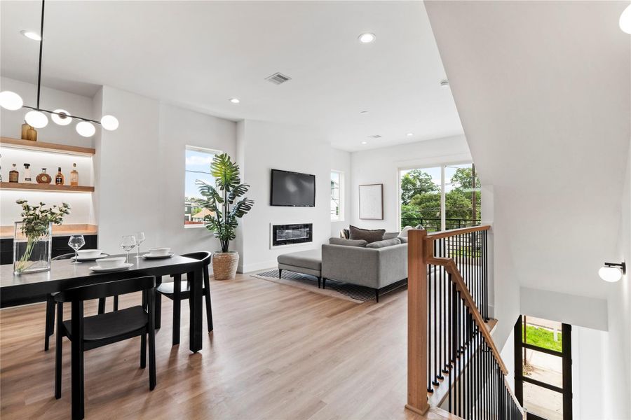 As you come up to the second floor, you’re greeted by an open dining area with a built-in dry bar, flowing seamlessly into the spacious living room with an electric fireplace and balcony views. As you come up to the second floor, you’re greeted by an open dining area with a built-in dry bar, flowing seamlessly into the spacious living room with an electric fireplace and balcony views.