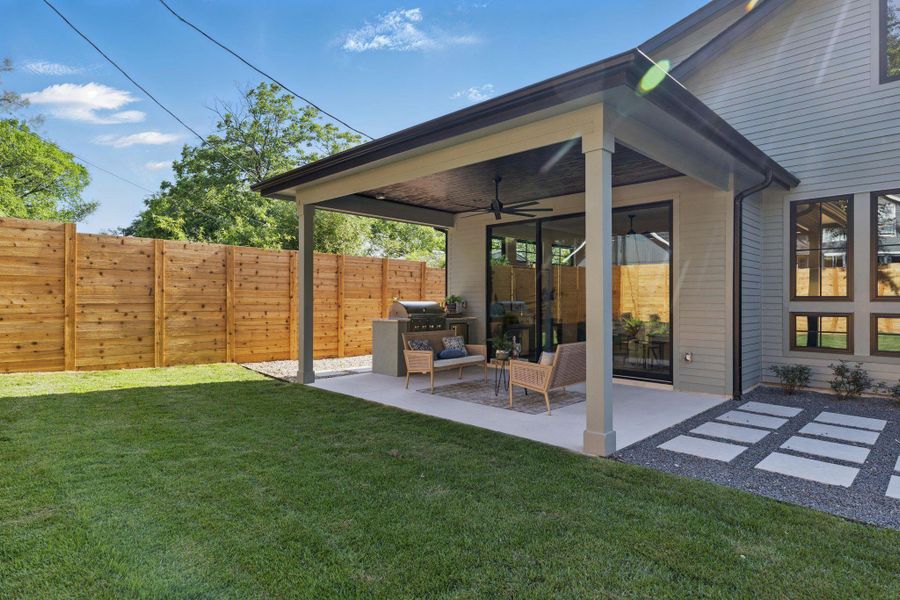 Fenced backyard featuring a ceiling fan and a patio area