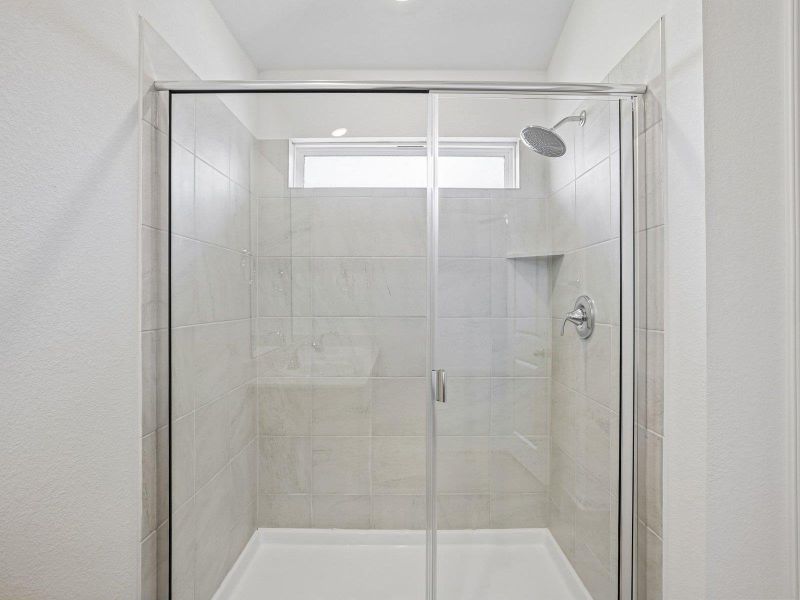 A sleek walk-in shower features large-format wall tiles and a glass enclosure.