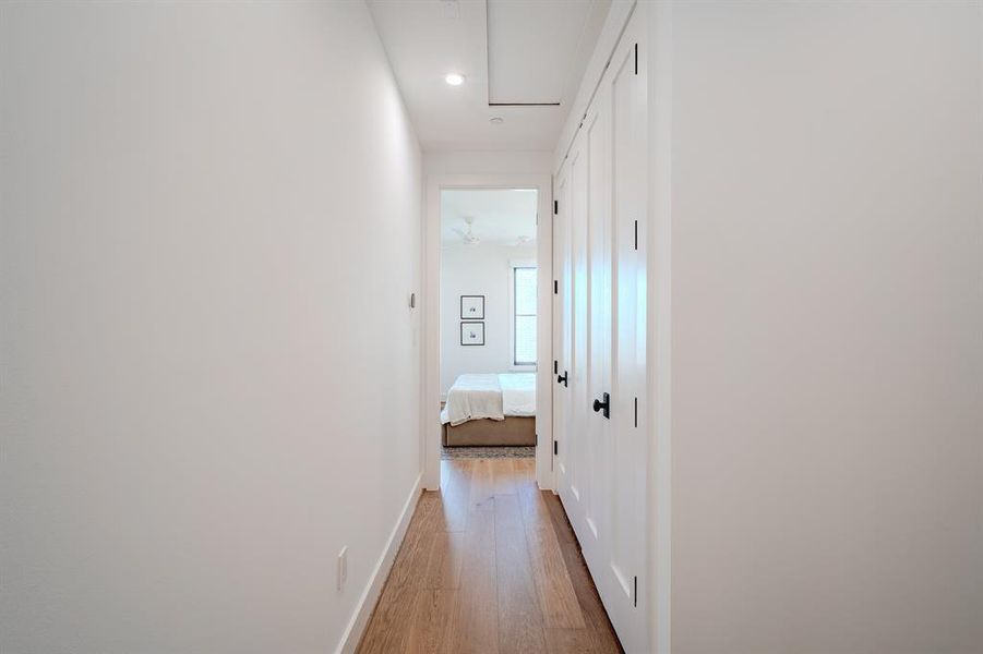 Hall with light wood-style flooring, attic access, and recessed lighting