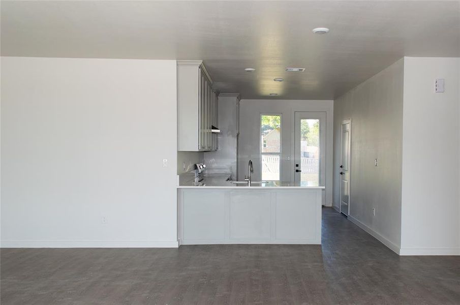 Kitchen featuring stove, a peninsula, and gray cabinets Kitchen featuring stove, a peninsula, and gray cabinets