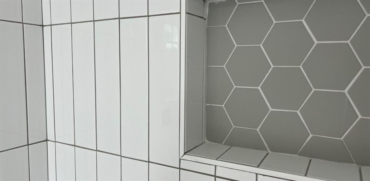 Chic Essentials Niche: Our primary bathroom's shampoo niche stands out with its grey hexagon-shaped tiles, beautifully contrasting against the tall stacked subway tiles for a crisp, fresh look that captures attention.