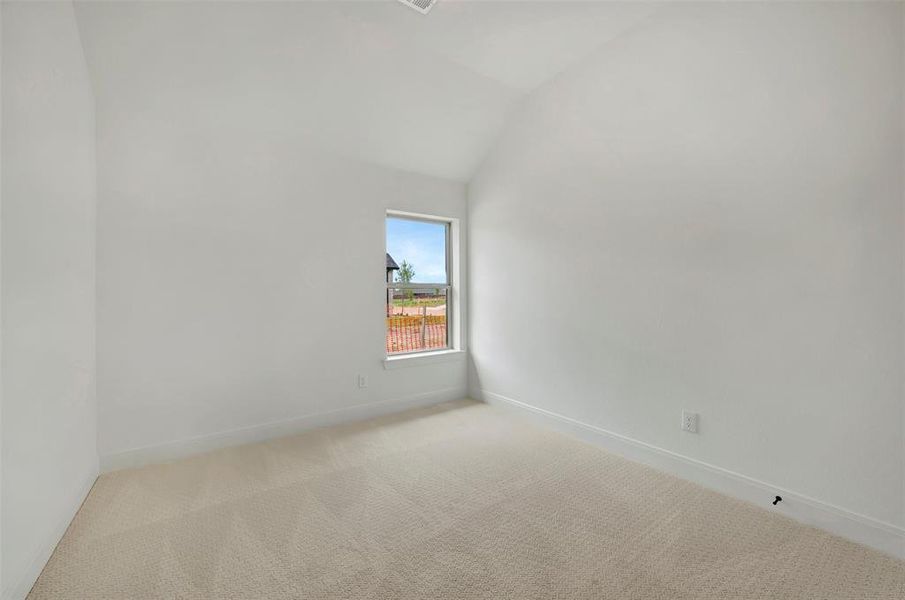 Carpeted interior room with an angled vaulted ceiling and a single window offering natural illumination