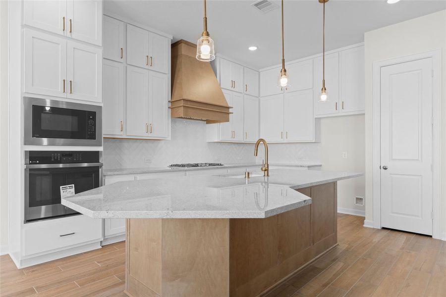 This close up view highlights the premium finishes, including granite countertops, built in convection oven, gas cooktop, and custom cabinetry, offering ample storage and workspace while maintaining a timeless and refined aesthetic.