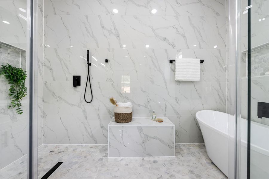 Spacious shower and soaking tub area featuring white marble-look tile walls, a freestanding tub, and matte black fixtures