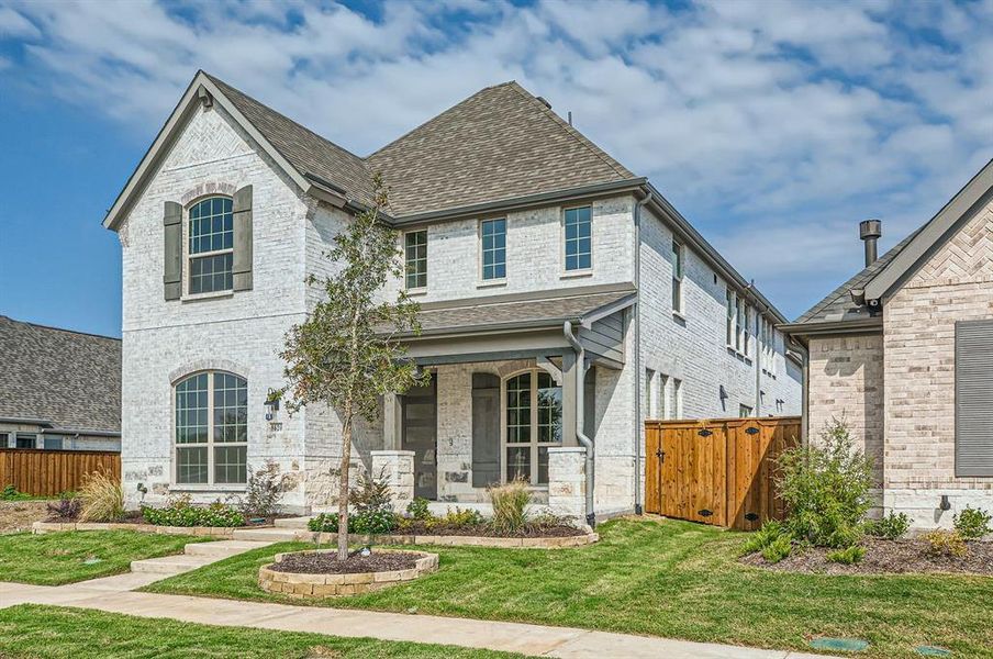 French country inspired facade with a front yard and covered porch