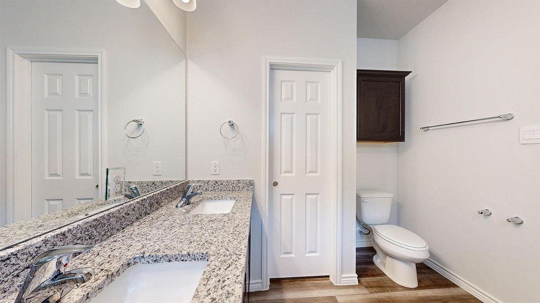 Bathroom featuring double vanity and dark wood-style floors