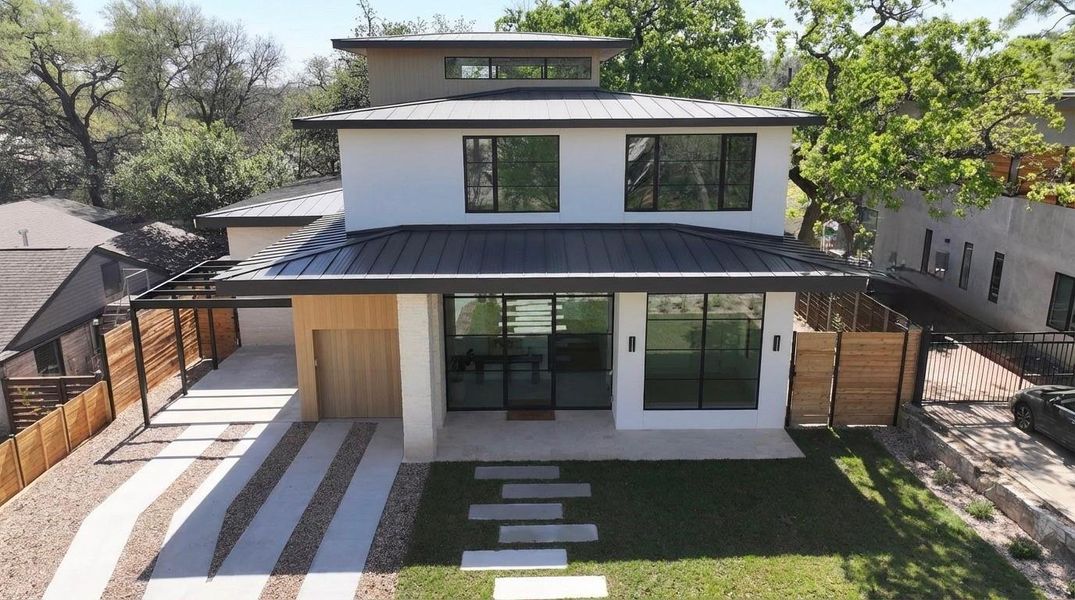 Back of property with a standing seam roof, a patio area, and a gate