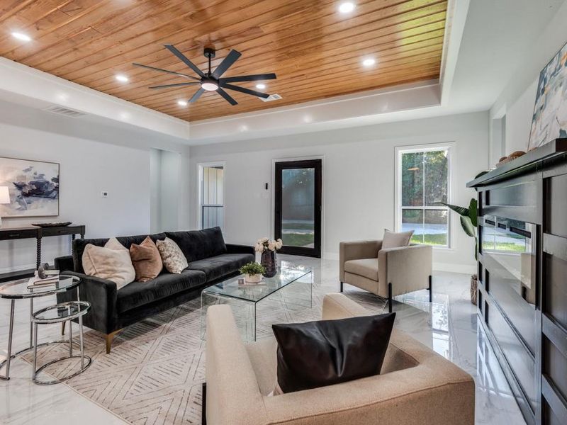 Living room featuring wood ceiling, light marble finish flooring, a raised ceiling, recessed lighting, and a ceiling fan.