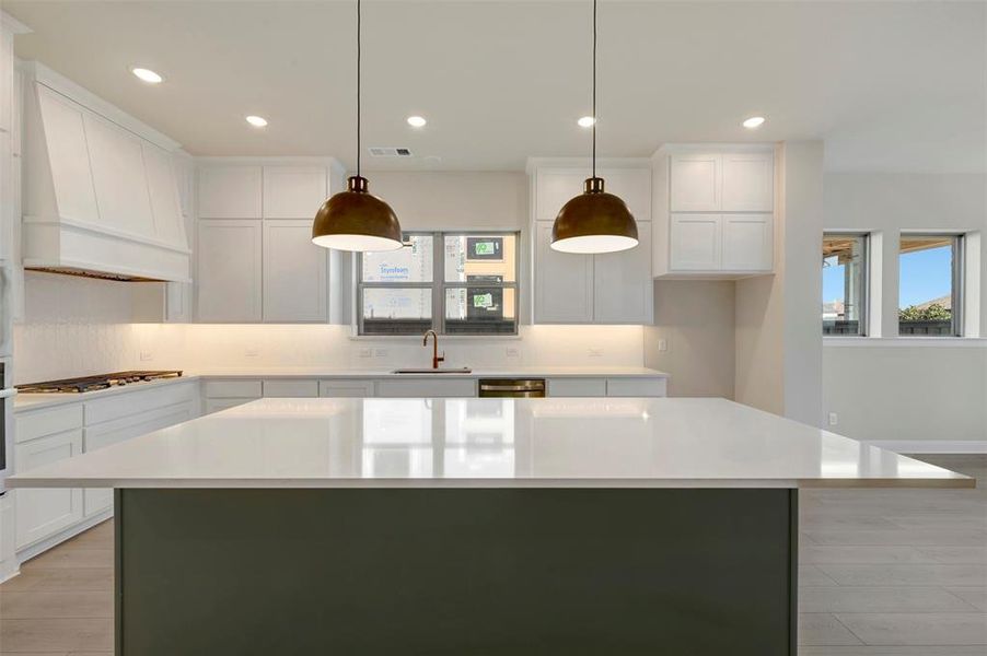Kitchen with light wood-type flooring, white cabinetry, a kitchen island, and hanging light fixtures
