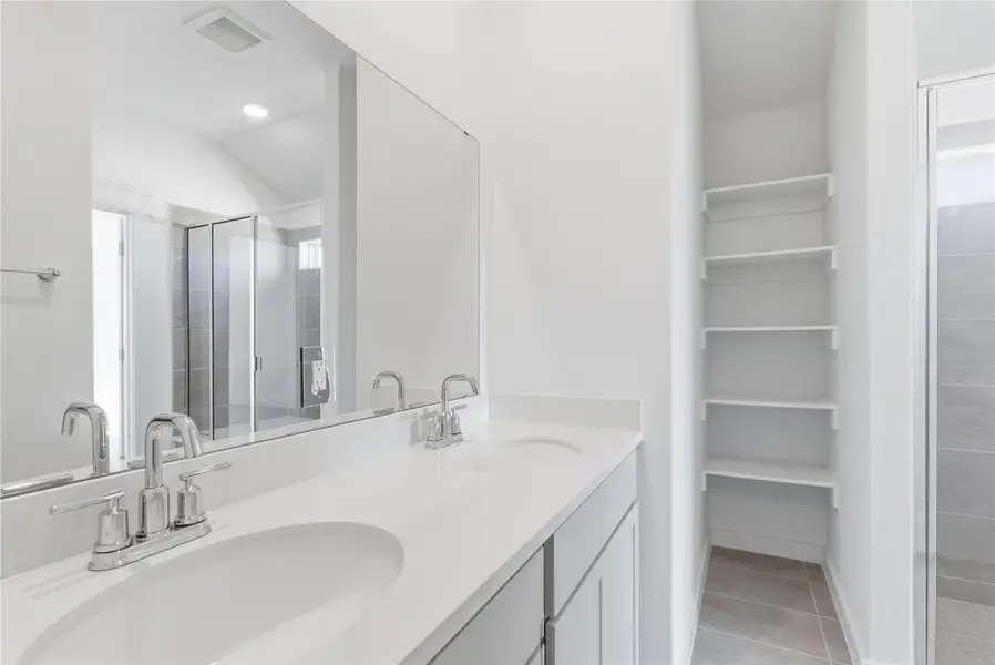 Full bath featuring a stall shower, light tile patterned floors, and double vanity
