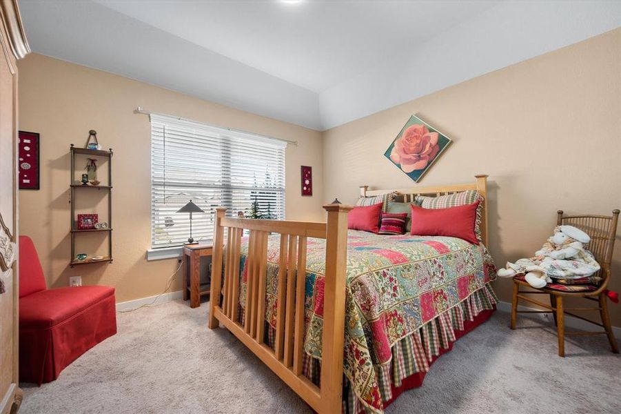 Bedroom featuring light colored carpet and lofted ceiling Bedroom featuring light colored carpet and lofted ceiling