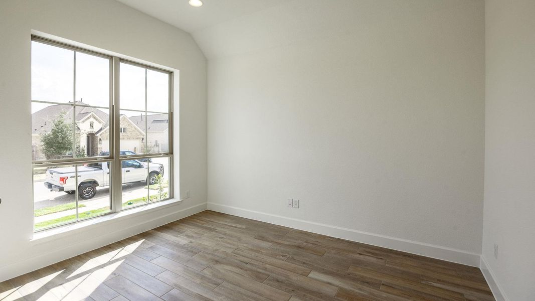 Spare room featuring wood finished floors, recessed lighting, a residential view, and vaulted ceiling Spare room featuring wood finished floors, recessed lighting, a residential view, and vaulted ceiling