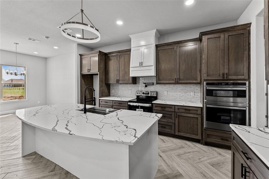 Kitchen with appliances with stainless steel finishes, dark brown cabinetry, decorative backsplash, light stone countertops, and recessed lighting Kitchen with appliances with stainless steel finishes, dark brown cabinetry, decorative backsplash, light stone countertops, and recessed lighting