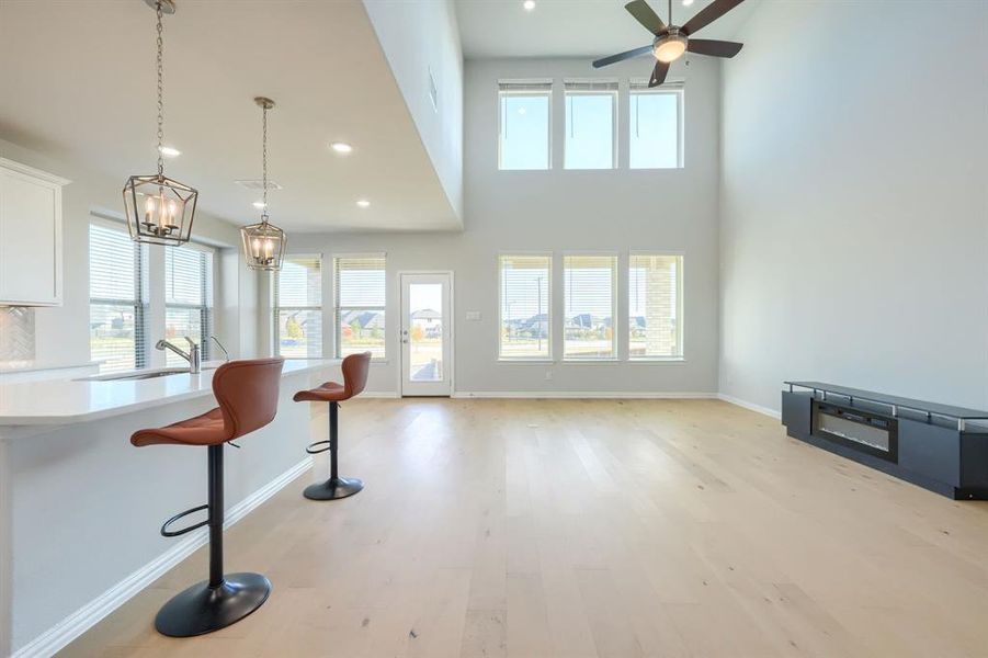 Living room with light wood finished floors, recessed lighting, a high ceiling, and a ceiling fan Living room with light wood finished floors, recessed lighting, a high ceiling, and a ceiling fan
