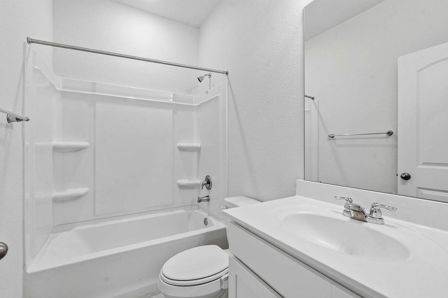 A well-appointed bathroom features a bright white tub-shower combination, modern vanity with an integrated sink, and an expansive mirror. A well-appointed bathroom features a bright white tub-shower combination, modern vanity with an integrated sink, and an expansive mirror.