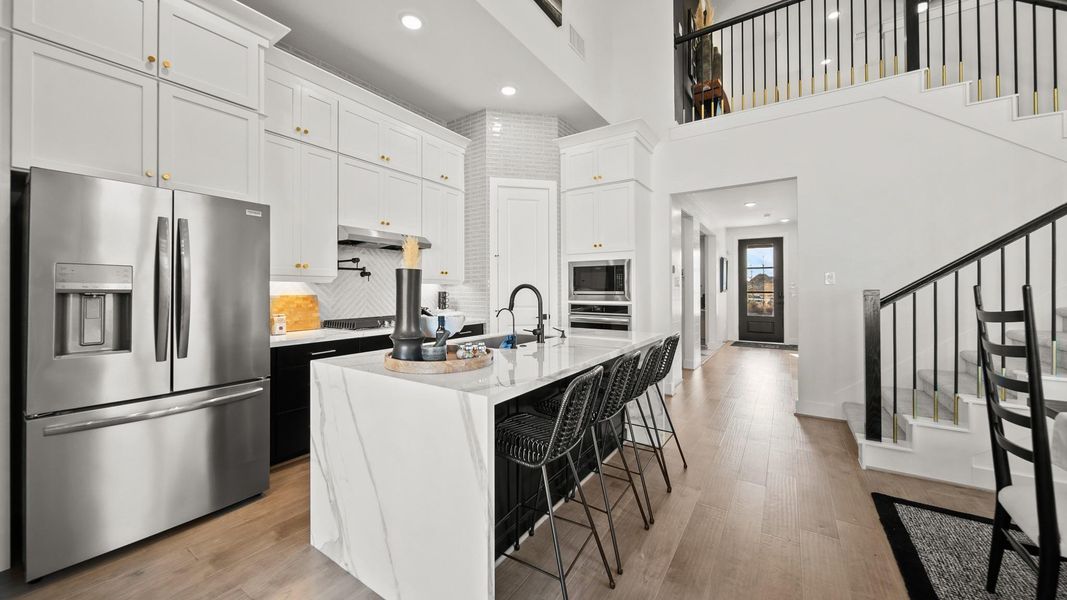 Boasting with character, this kitchen highlights two-toned cabinetry with stark white upper cabinets stacked high to the 12' ceiling, and moody dark lower and island cabinets. Boasting with character, this kitchen highlights two-toned cabinetry with stark white upper cabinets stacked high to the 12' ceiling, and moody dark lower and island cabinets.