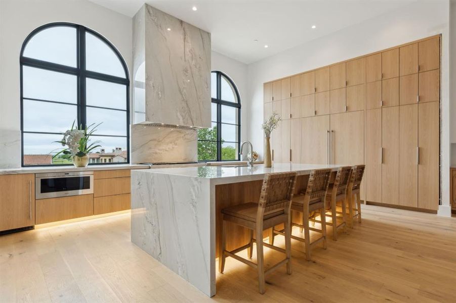 Kitchen featuring modern built-in cabinets, White oak floors, Wolf & SubZero appliances, light stone countertops, and recessed lighting Kitchen featuring modern built-in cabinets, White oak floors, Wolf & SubZero appliances, light stone countertops, and recessed lighting