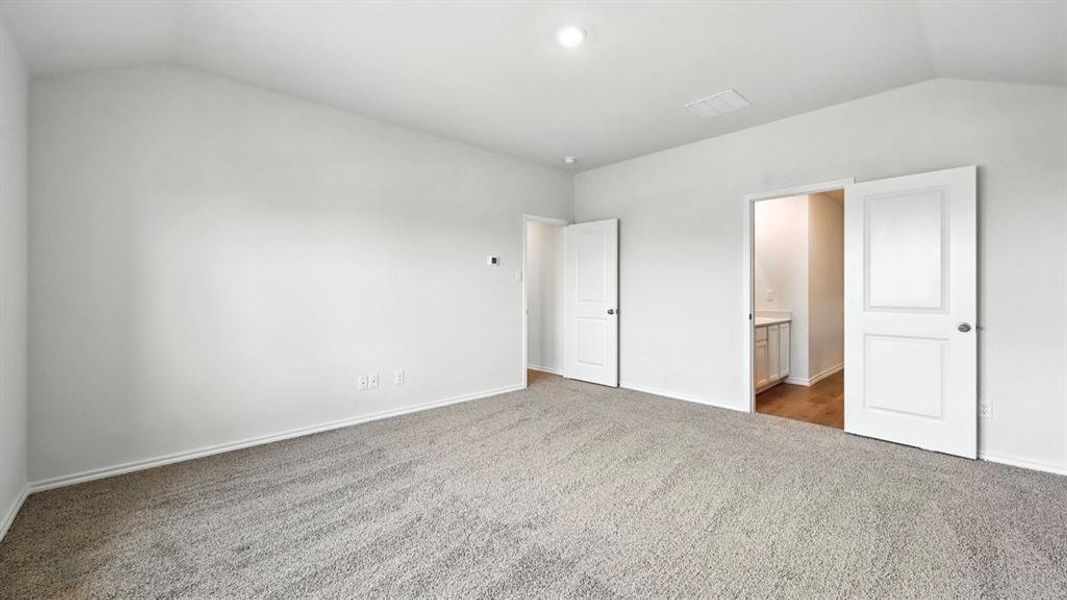 Unfurnished bedroom with vaulted ceiling, carpet flooring, and ensuite bathroom